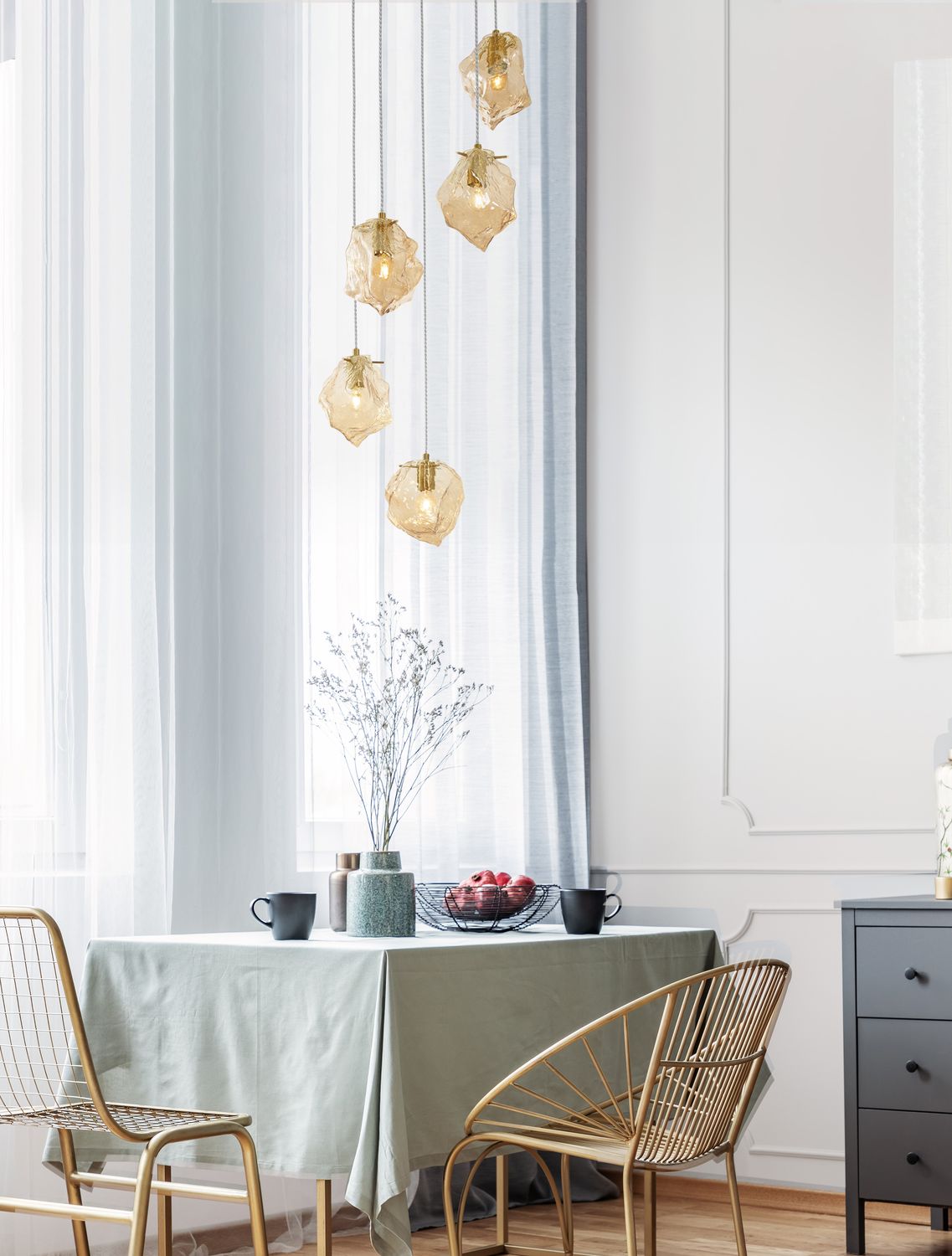 Suspension dorée à cinq verres ambrés suspendue au-dessus d'une table de salle à manger