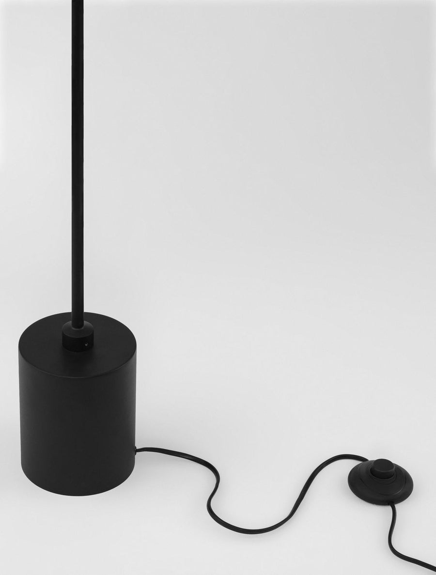 Détail du socle cylindrique noir, du câble et de l'interrupteur au sol