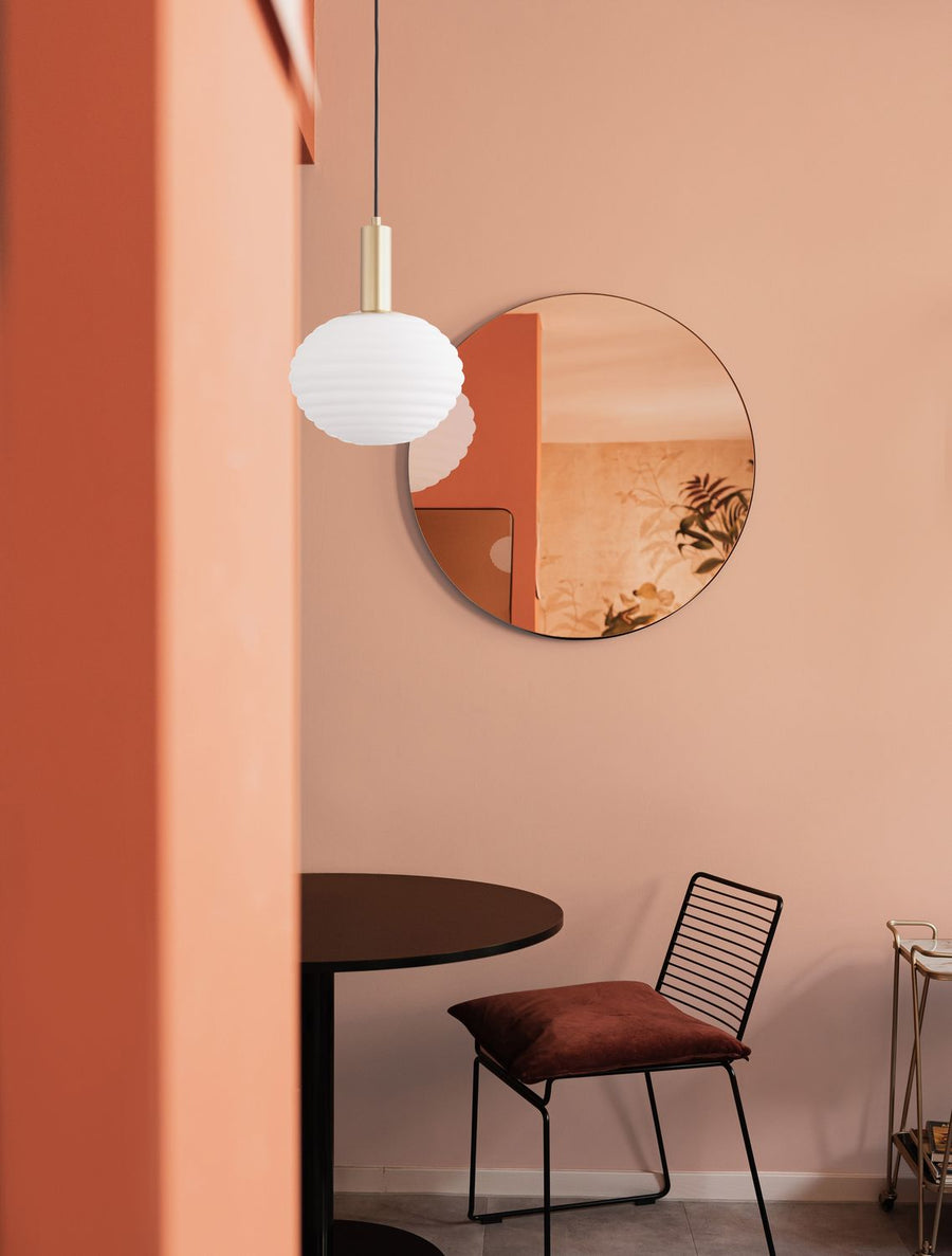 Suspension dorée suspendue au-dessus d'une table ronde dans un intérieur pêche