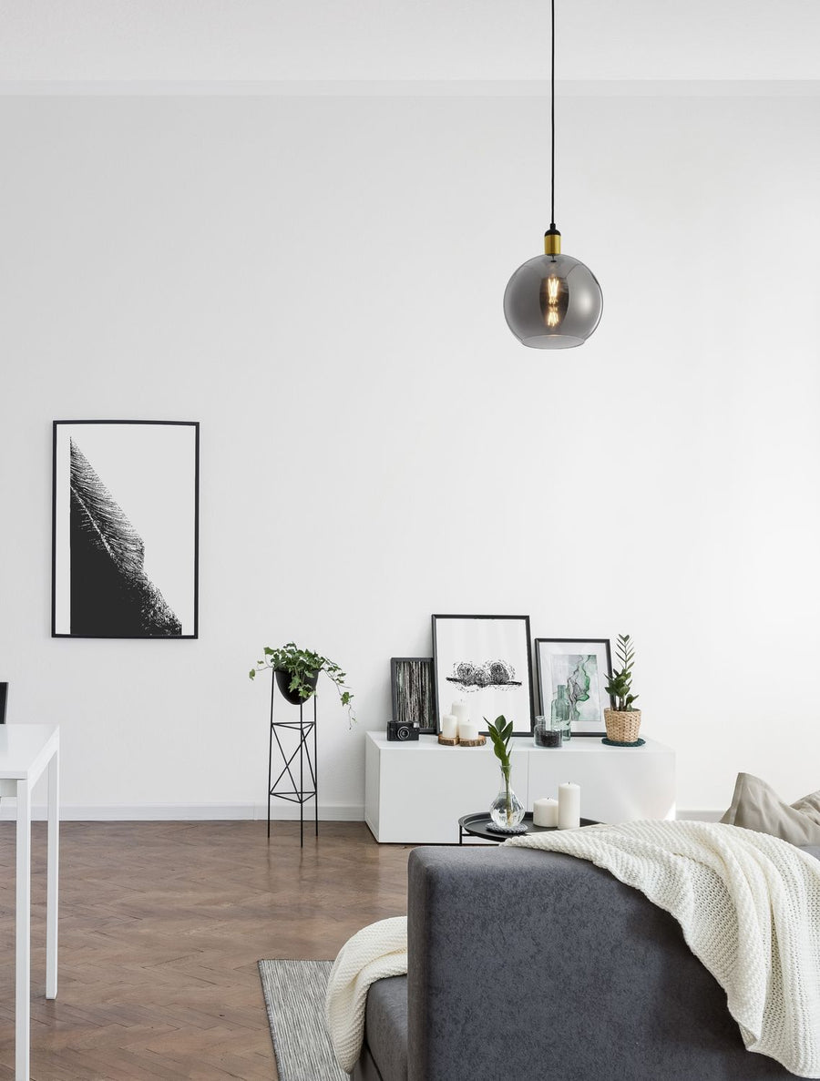 Suspension boule en verre fumé allumée, installée dans un salon au-dessus d'un canapé