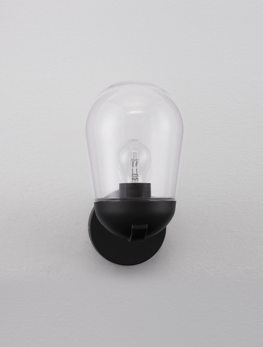 Applique fixée sur un mur gris clair, ampoule éteinte sous la cloche de verre