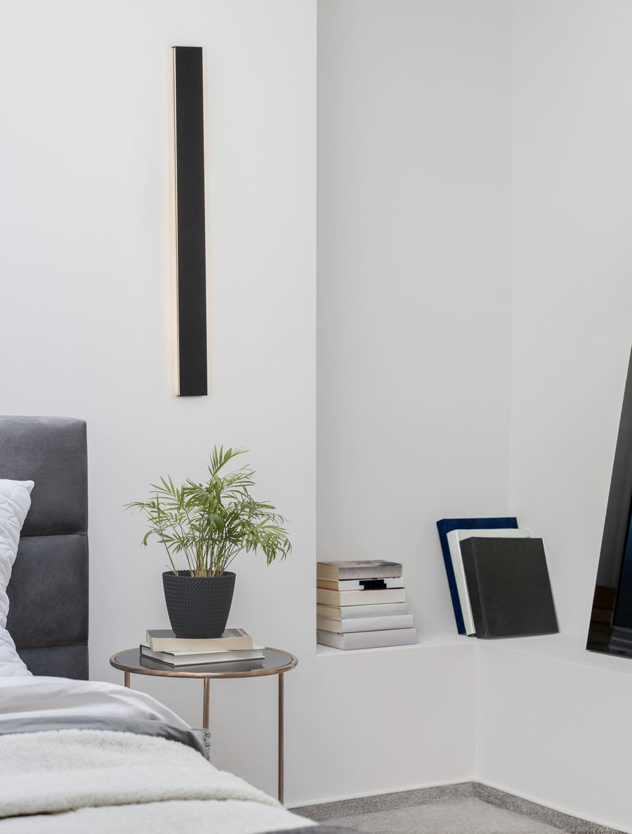 Applique murale noire allumée au-dessus d'une table de chevet dans une chambre