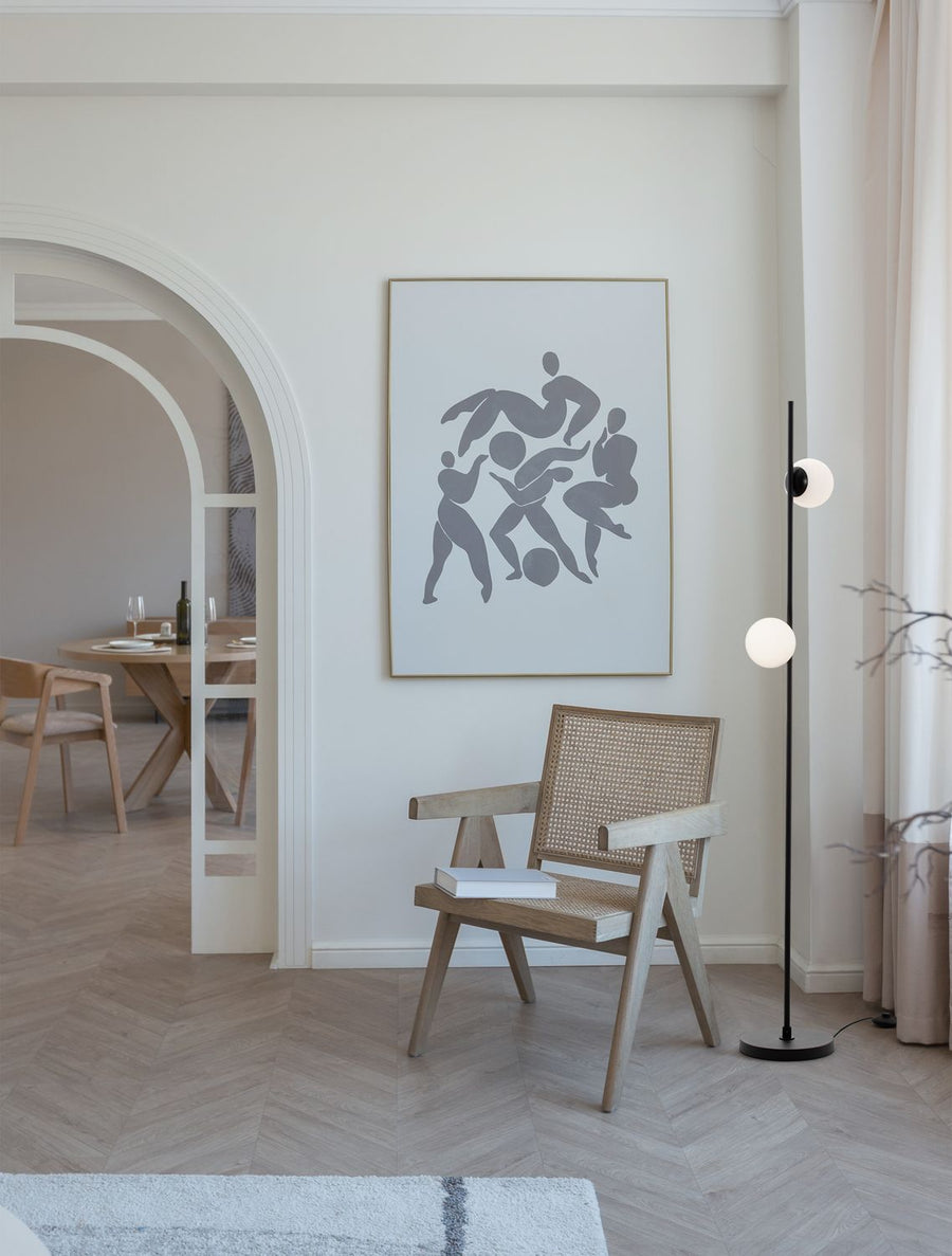 Lampadaire noir allumé dans un salon, près d'un fauteuil en cannage
