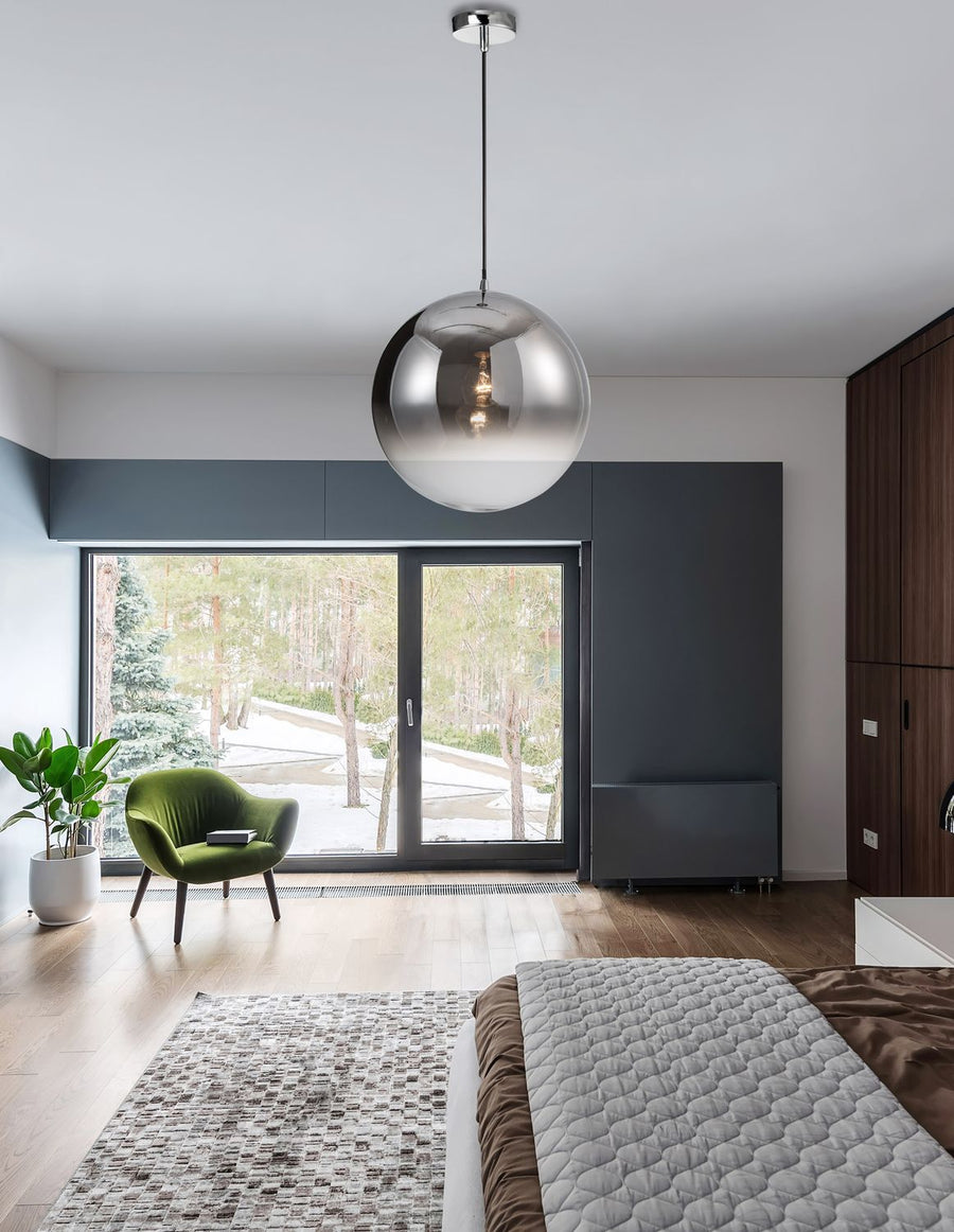 Suspension boule chromée éclairée dans une chambre moderne, avec lit et baie vitrée sur forêt enneigée.
