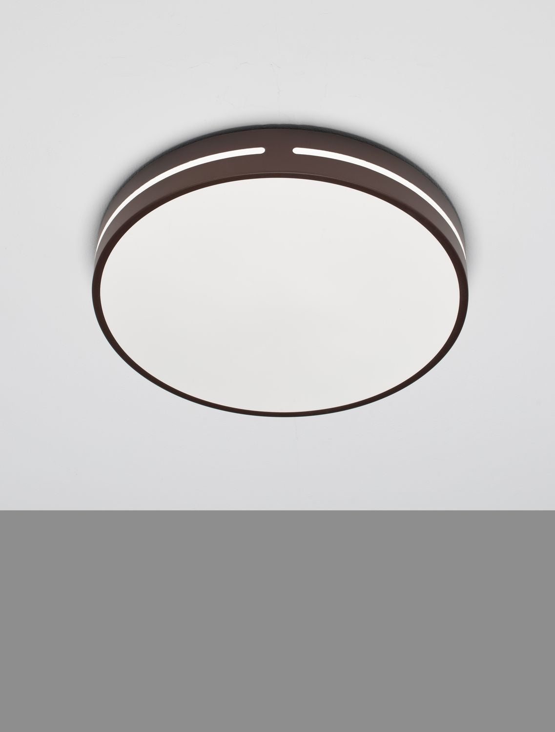 Plafonnier rond marron fixé au plafond, vue de dessous sur fond gris