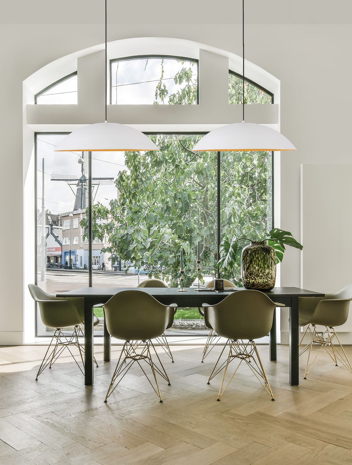Deux suspensions blanches suspendues au-dessus d'une table de salle à manger devant une grande fenêtre.