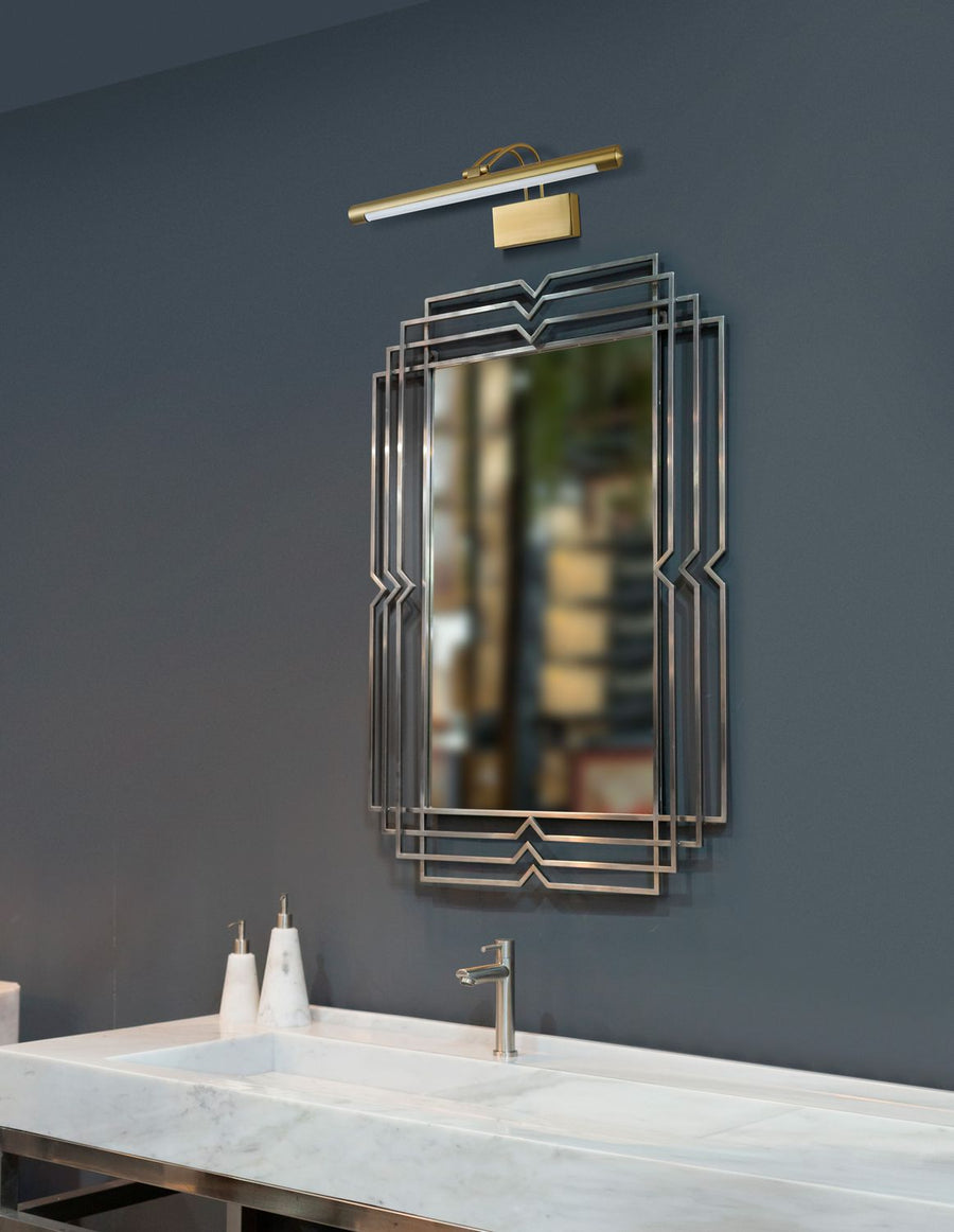 Applique murale en laiton doré installée au-dessus d'un miroir dans une salle de bain