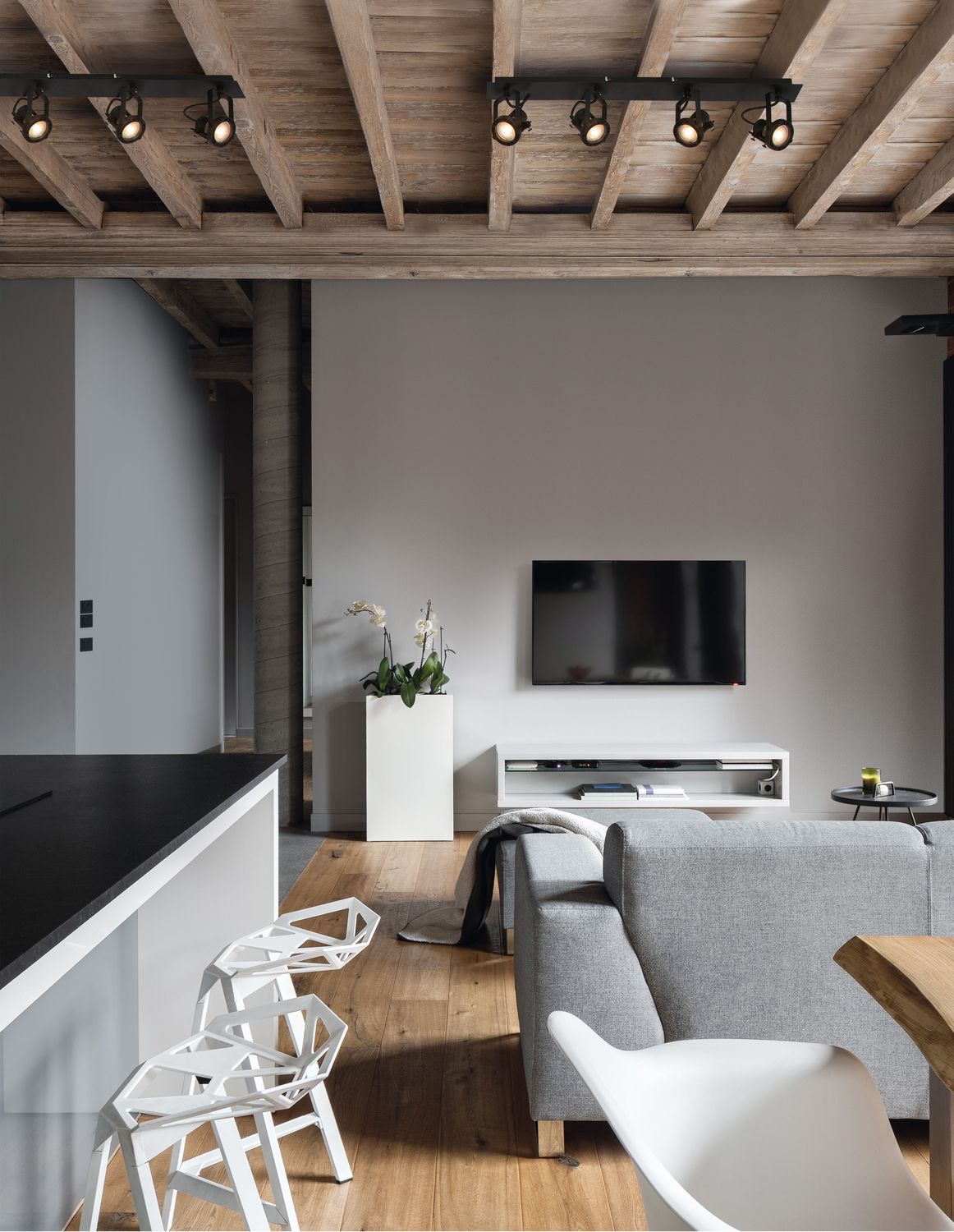 Plafonnier quatre spots noirs installé sur plafond à poutres en bois, vue d'ambiance