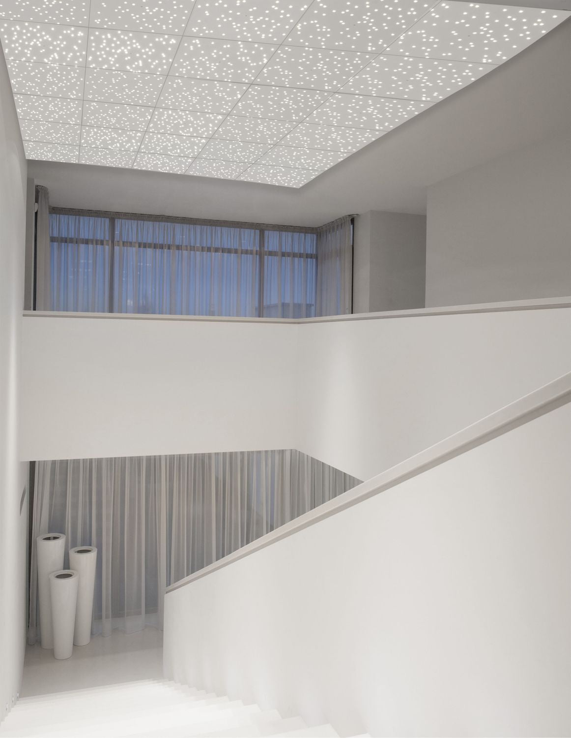 Plafonnier blanc éclairé dans une cage d'escalier minimaliste, effet ciel étoilé au plafond
