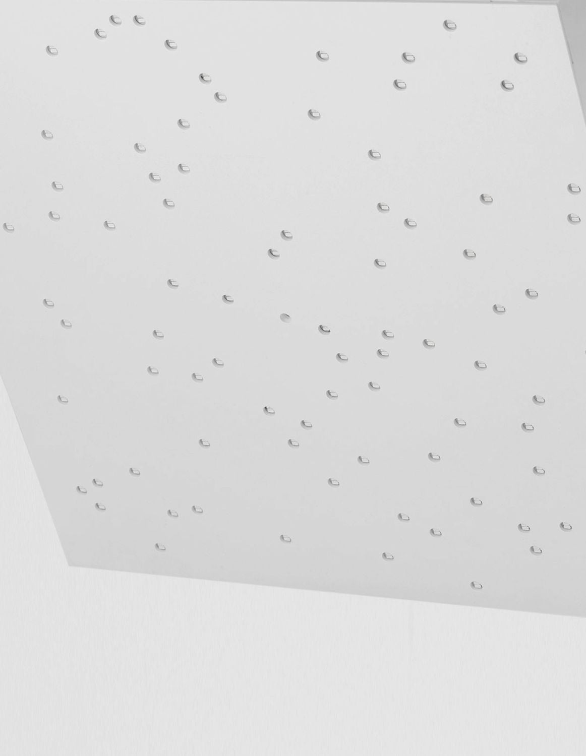 Gros plan sur les perforations éteintes du panneau blanc, trous découpés en quinconce