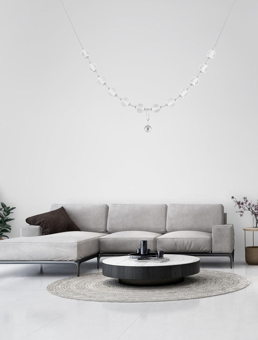 Luminaire suspendu en chapelet de boules transparentes dans un salon blanc contemporain