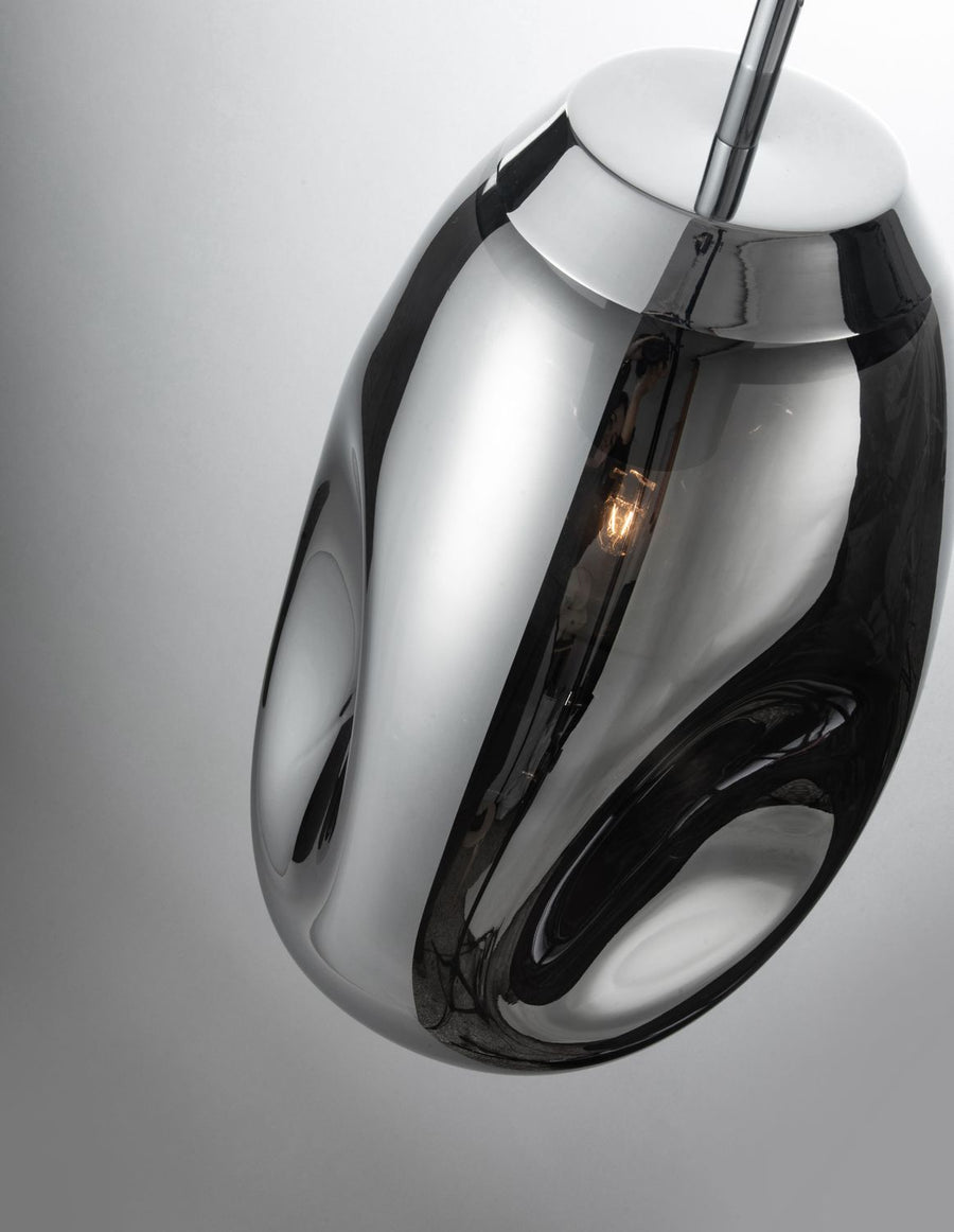 Détail rapproché du verre fumé et de l'ampoule allumée à l'intérieur de la suspension.