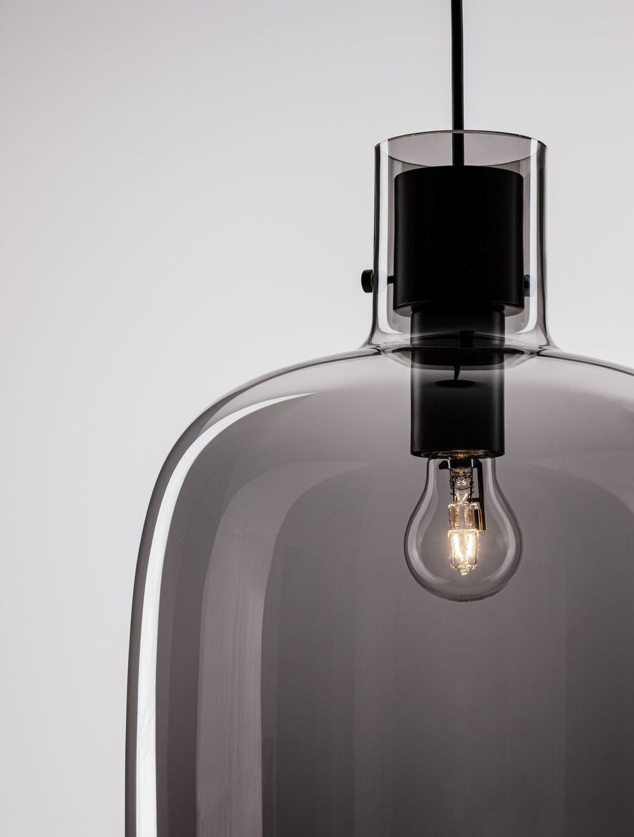 Gros plan sur la douille noire et l'ampoule à filament sous le verre fumé