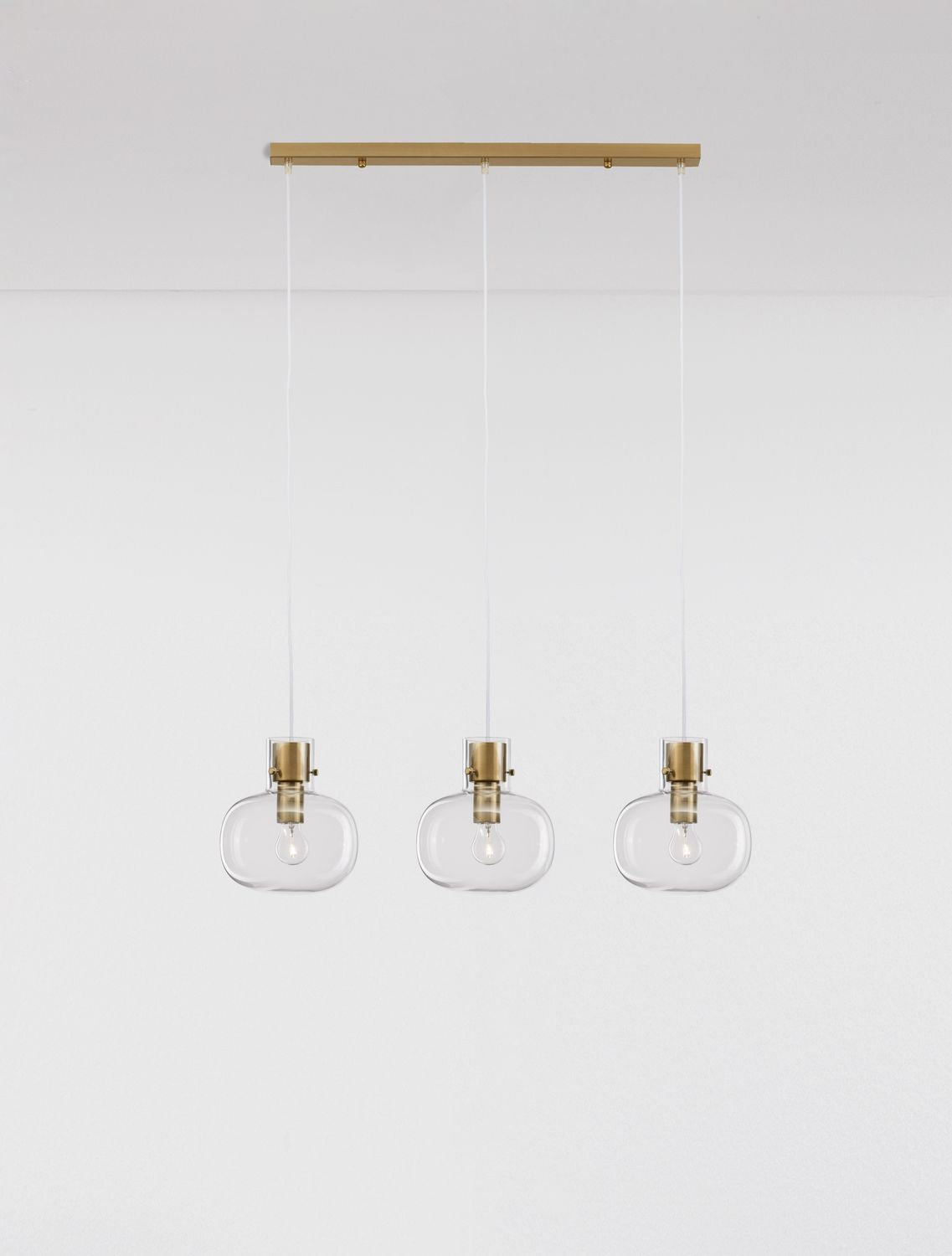 Trois suspensions en verre transparent suspendues sous leur barre de fixation