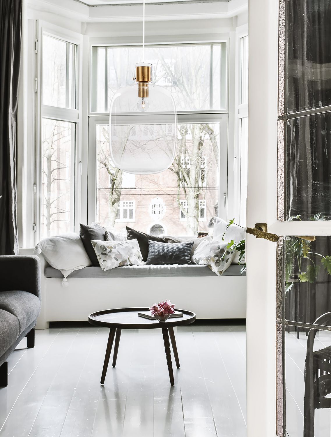 Suspension en verre transparent éclairée devant une grande fenêtre, dans un intérieur très lumineux