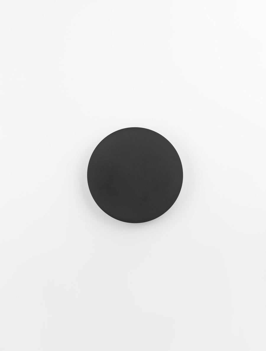 Vue de face du disque noir avec halo lumineux diffus sur le mur