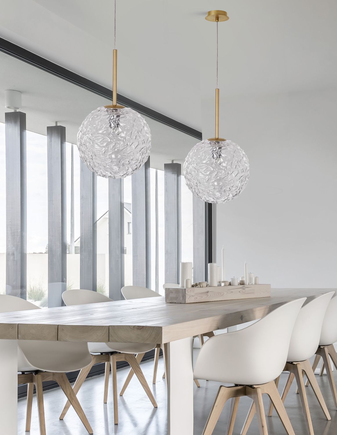 Mise en ambiance : deux suspensions dorées au-dessus d'une table à manger en bois clair