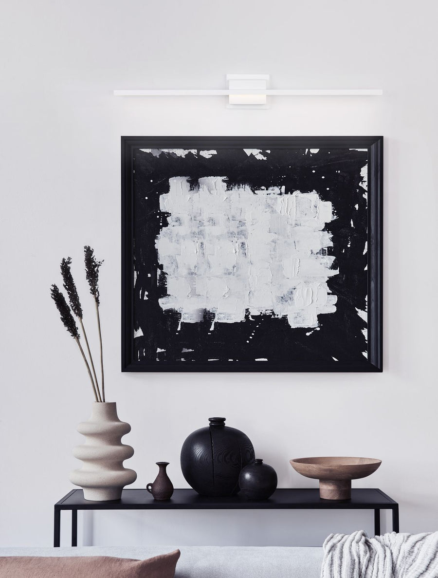 Applique murale blanche allumée au-dessus d'un tableau abstrait noir et blanc