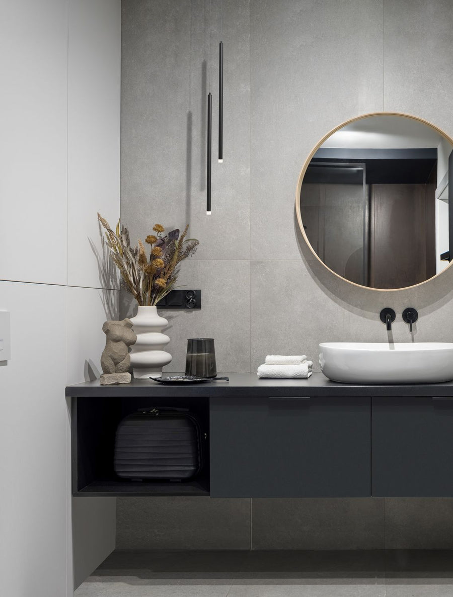 Suspension noire fine installée dans une salle de bain moderne au-dessus du meuble vasque