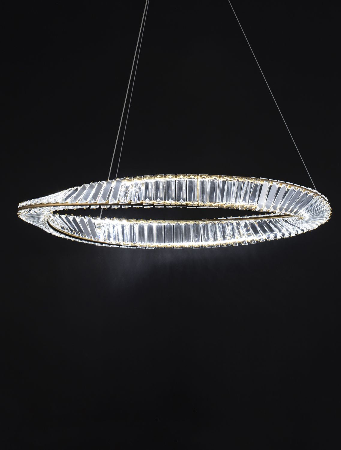 Luminaire allumé dans le noir, halo lumineux traversant les prismes