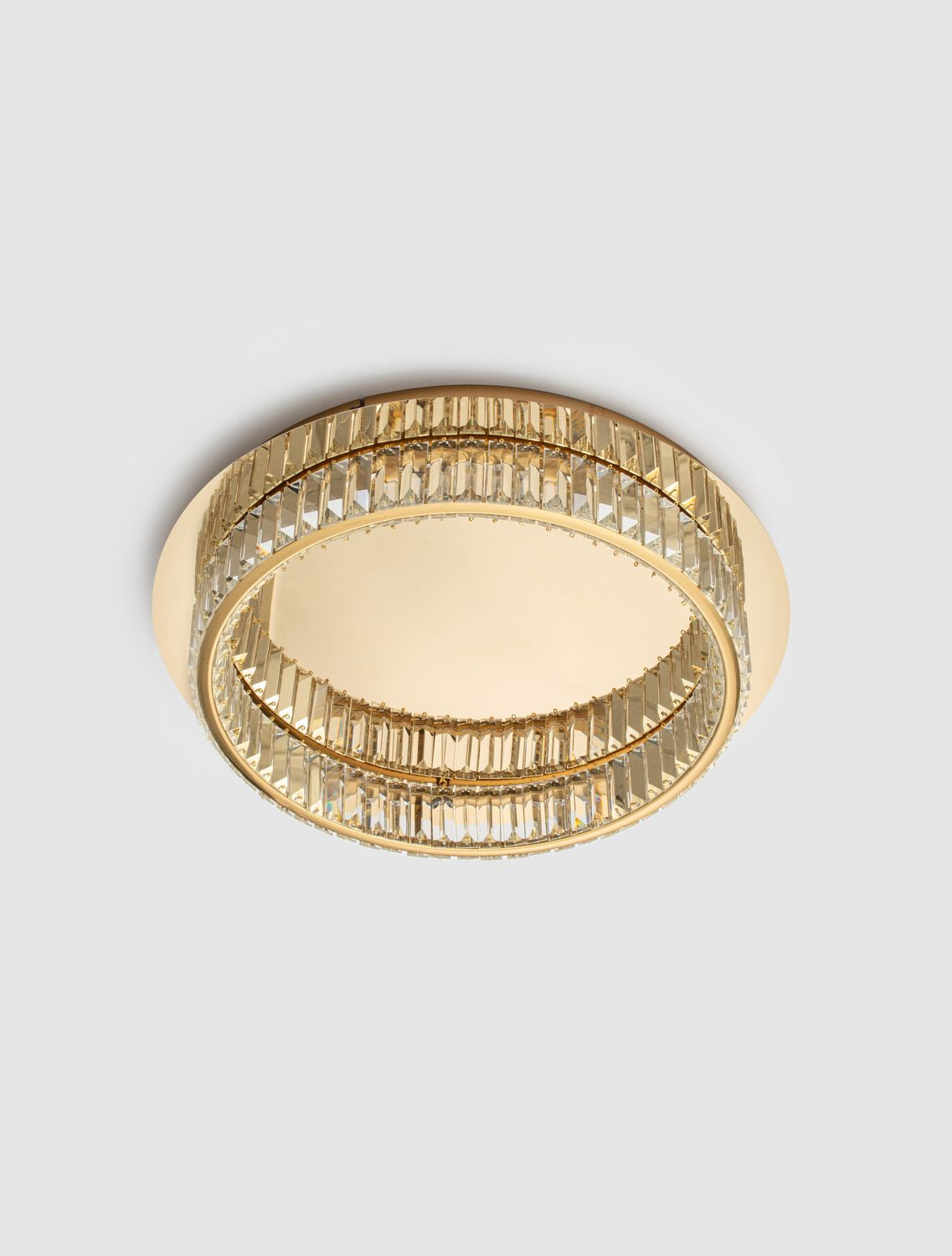 Plafonnier rond allumé vu de dessous sur fond clair, cercle de cristaux scintillants