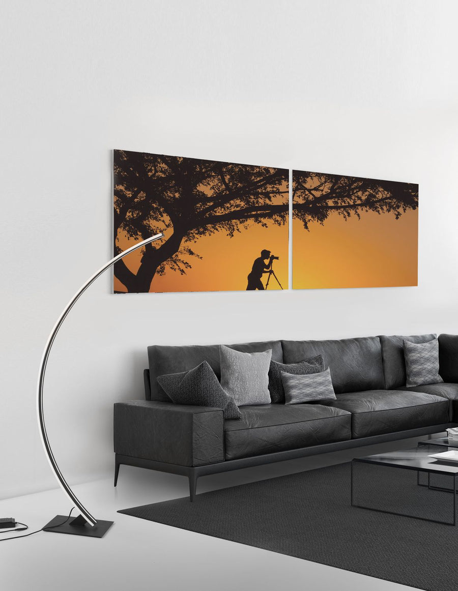 Lampadaire arc noir allumé dans un salon devant un canapé en cuir