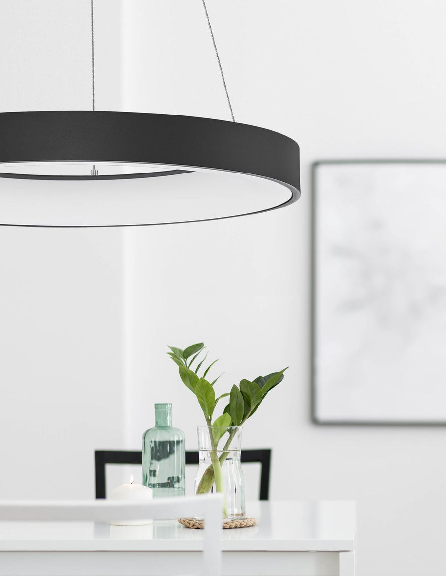 Suspension ronde noire éclairant une table dressée avec plante et bougie