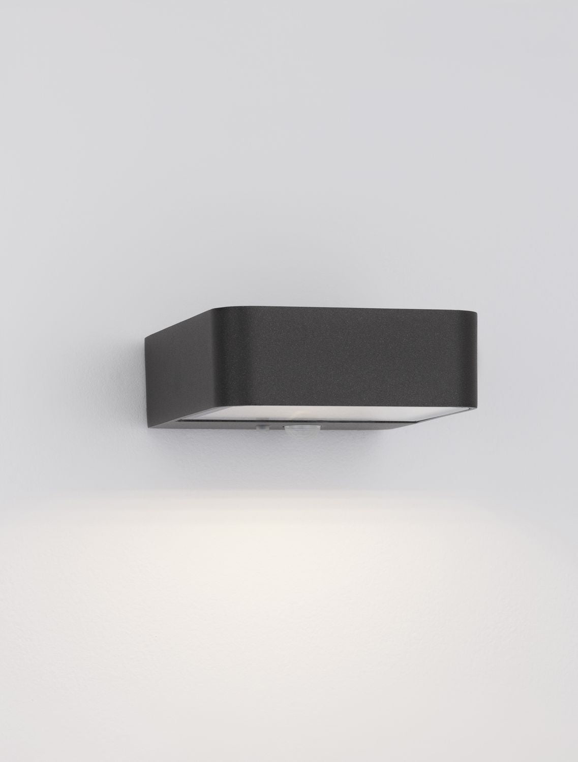 Luminaire mural allumé diffusant un halo lumineux blanc vers le bas