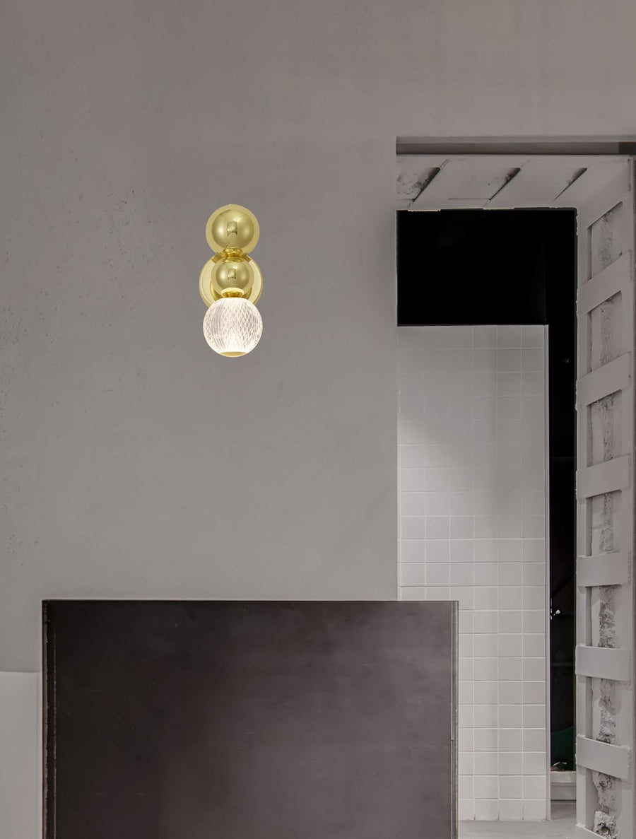 Applique murale dorée fixée sur un mur gris dans un intérieur en travaux