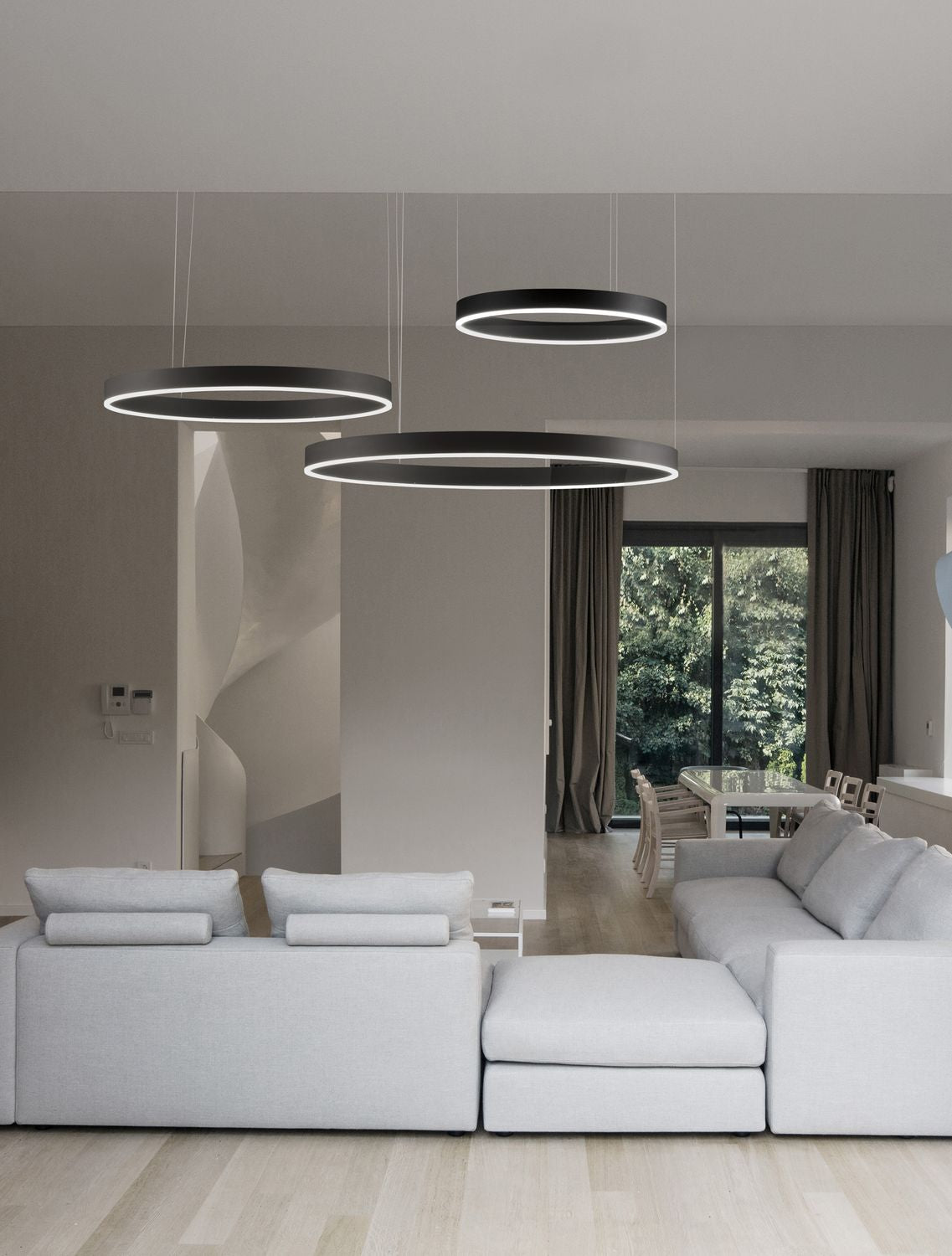 Mise en ambiance d'un salon moderne avec trois anneaux noirs suspendus au-dessus du canapé