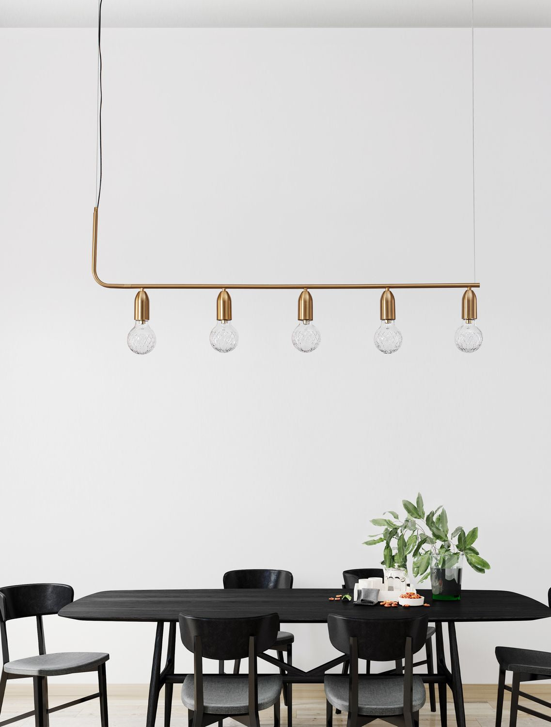 Suspension linéaire en laiton installée au-dessus d'une table noire dans une salle à manger
