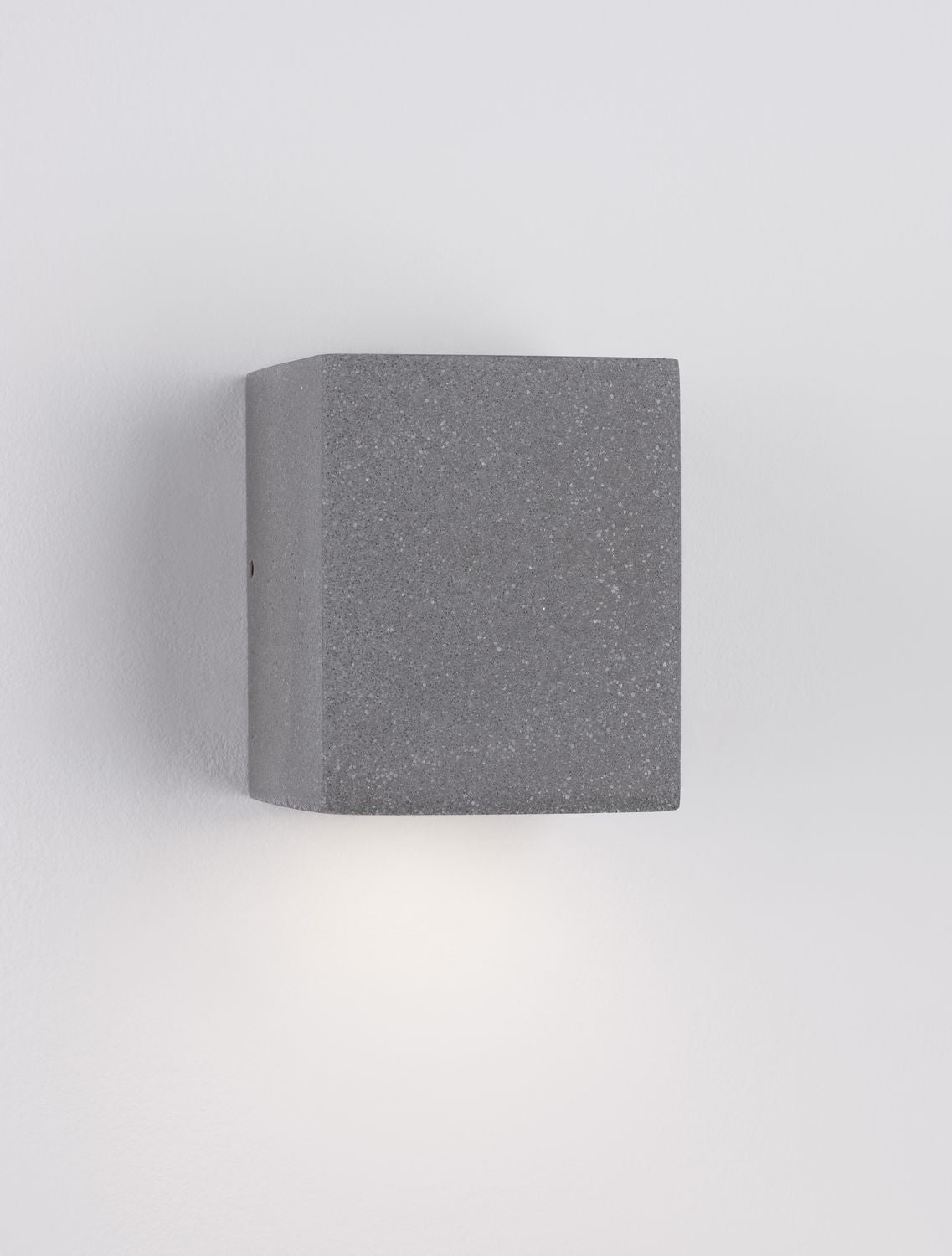 Vue de profil de l'applique grise allumée, halo lumineux diffusé vers le bas