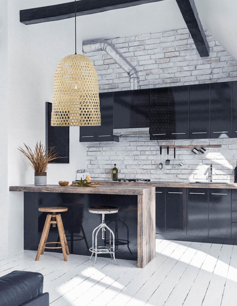 Suspension en rotin beige installée au-dessus d'un îlot de cuisine aux façades noires.