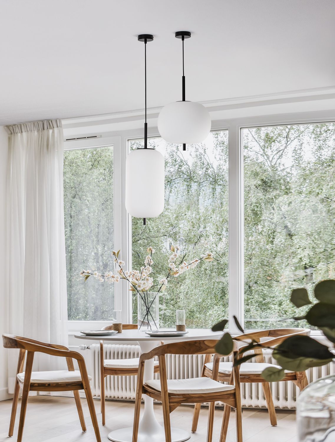 Suspension blanche allumée au-dessus d'une table à manger dans un intérieur clair