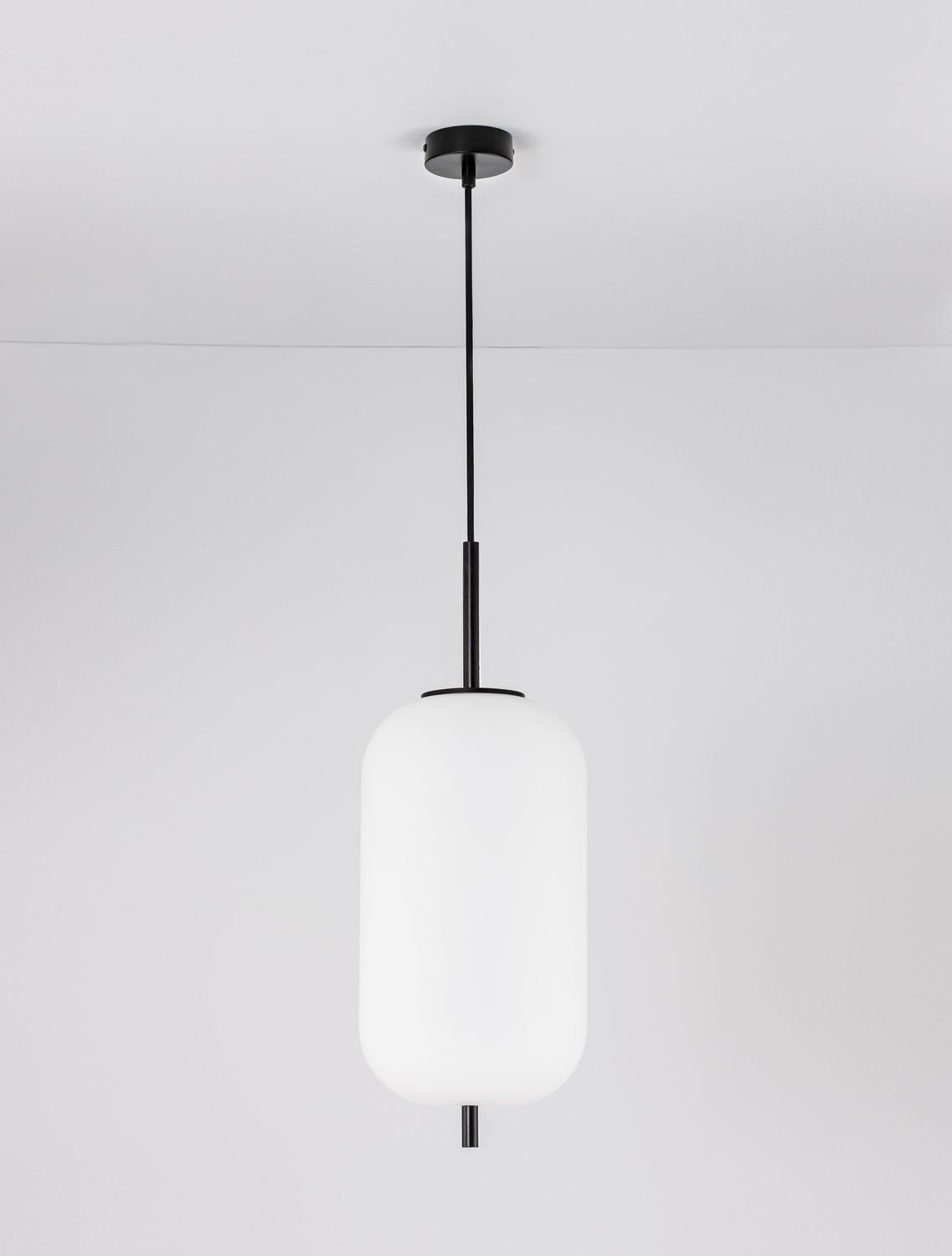 Vue de face sur fond gris clair, abat-jour cylindrique blanc et tige noire