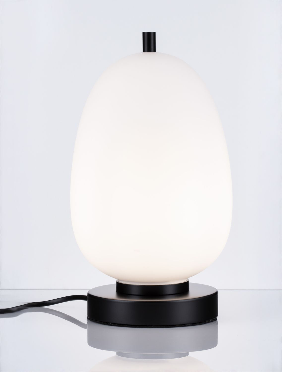 Lampe allumée, globe lumineux blanc, base noire, vue de face sur fond gris.