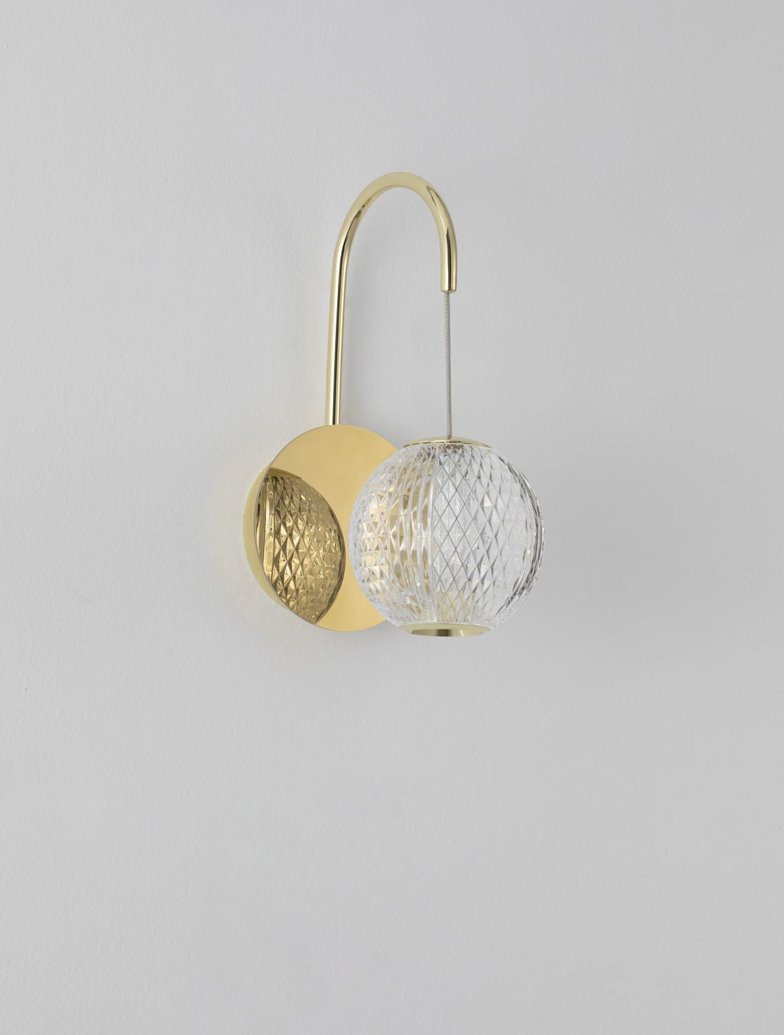 Détail rapproché de la sphère en verre à motif losangé et de la finition dorée.