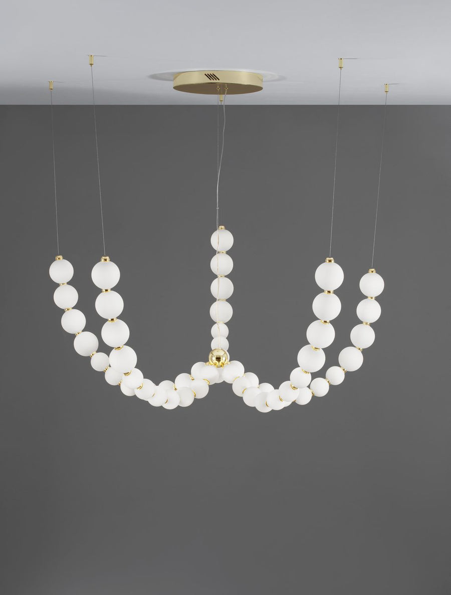 Luminaire suspendu vu de face sur fond gris, rosace et finitions dorées
