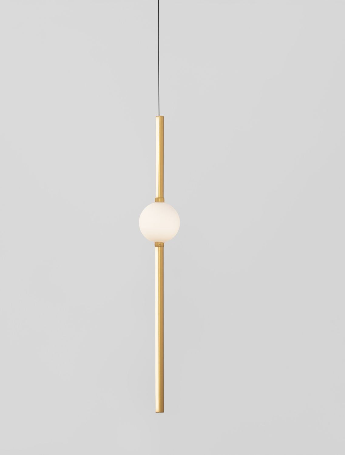 Gros plan sur la sphère blanche lumineuse et la tige dorée verticale du luminaire.