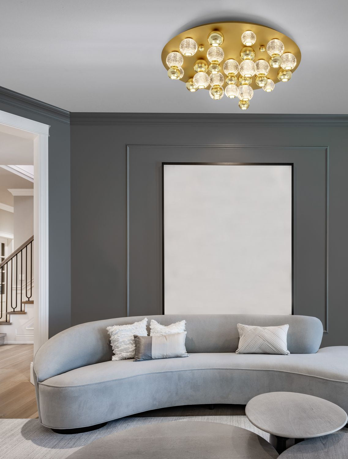 Plafonnier doré installé au plafond d'un salon gris avec canapé courbe