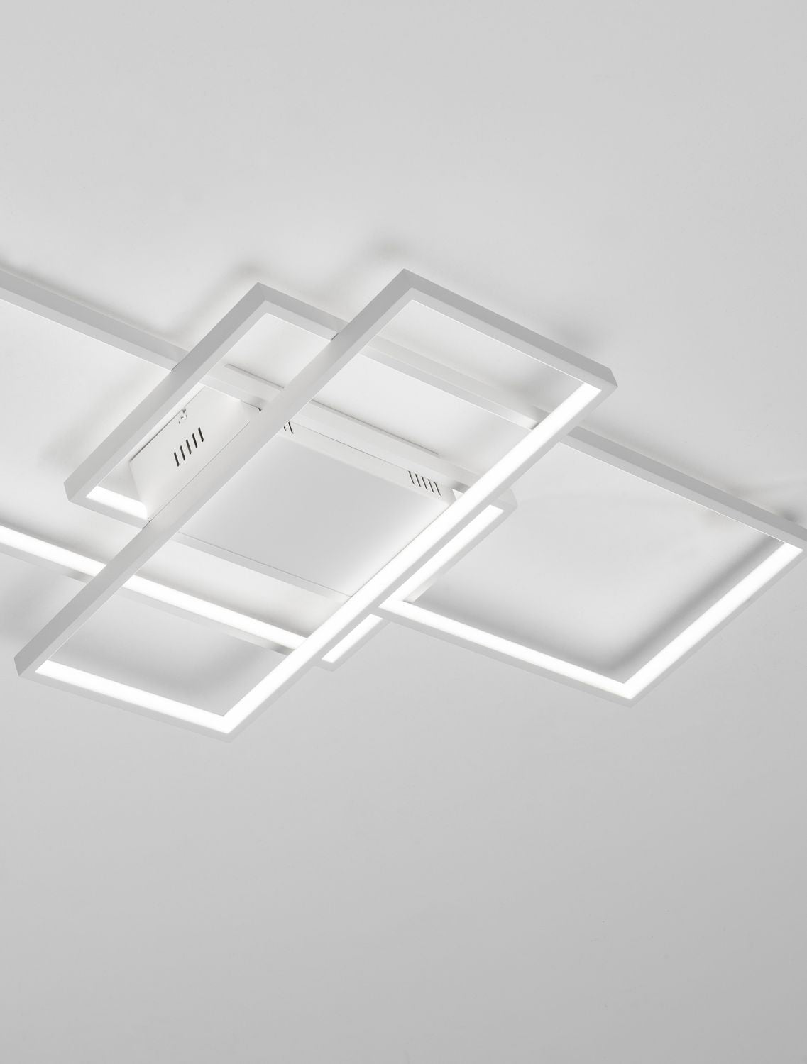 Plafonnier blanc allumé, cadres rectangulaires imbriqués fixés au plafond.