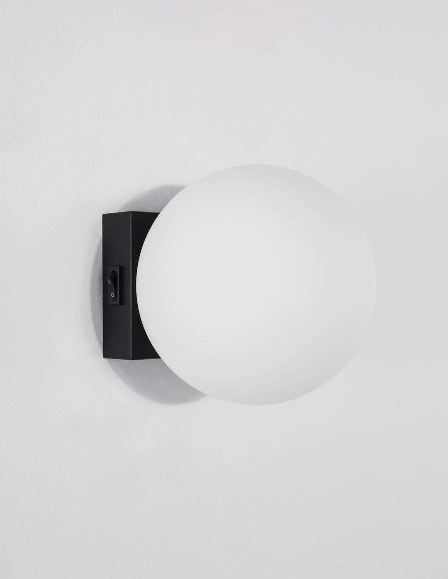 Profil de l'applique murale noire avec son interrupteur, globe blanc et ombre portée.
