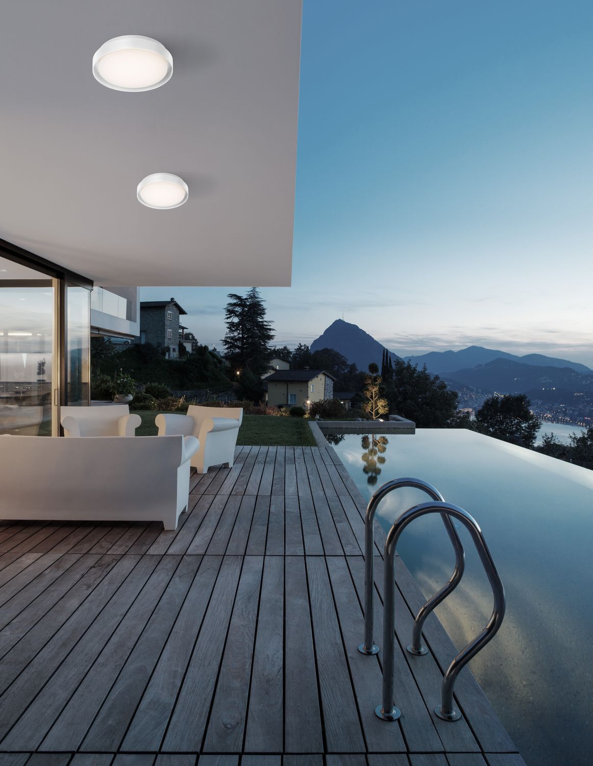 Luminaire rond blanc éclairant une terrasse de villa au bord d'une piscine au crépuscule