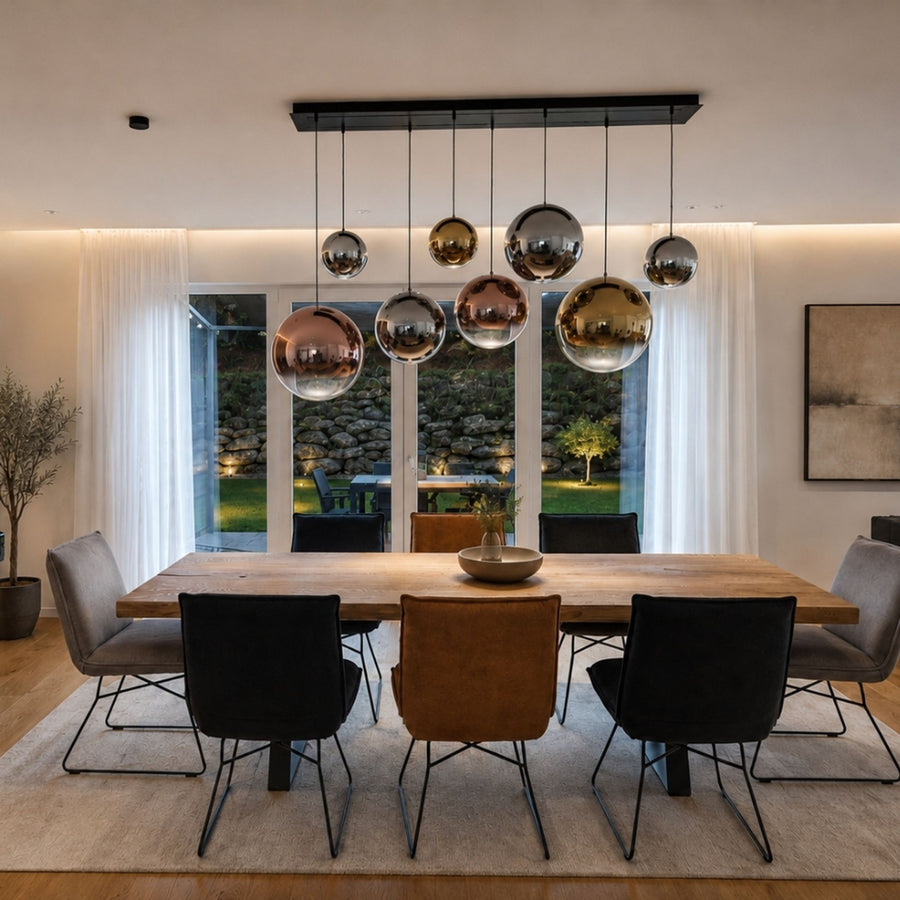Grande salle à manger avec sept globes suspendus sur une platine linéaire noire au-dessus d'une table.