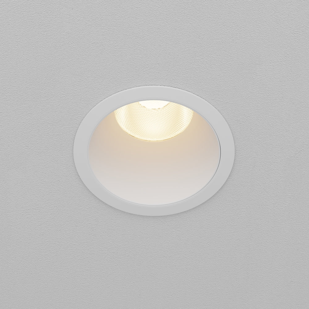 Spot encastré blanc vu de face, monté dans un plafond gris texturé.