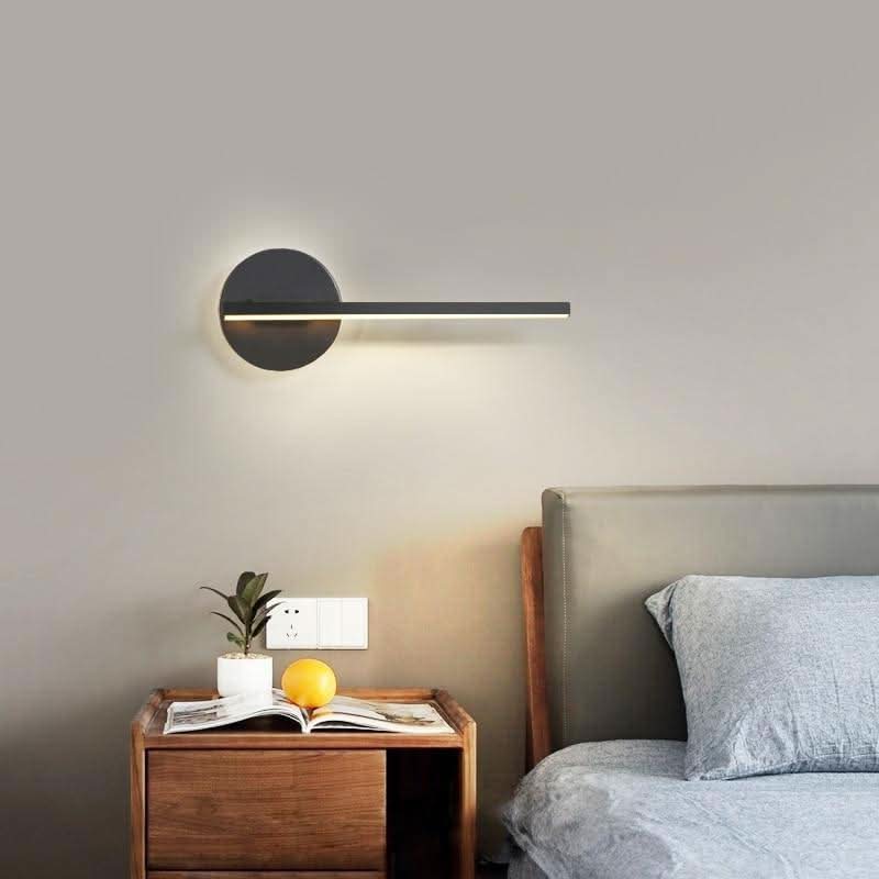 Mise en ambiance chambre, applique noire allumée au-dessus d'une table de nuit
