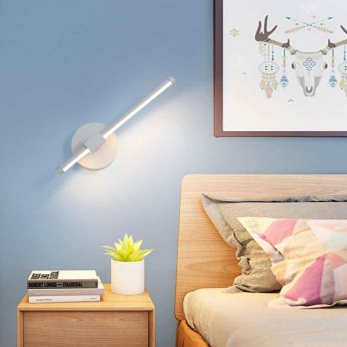 Applique blanche inclinée dans une chambre bleue avec tête de lit en bois