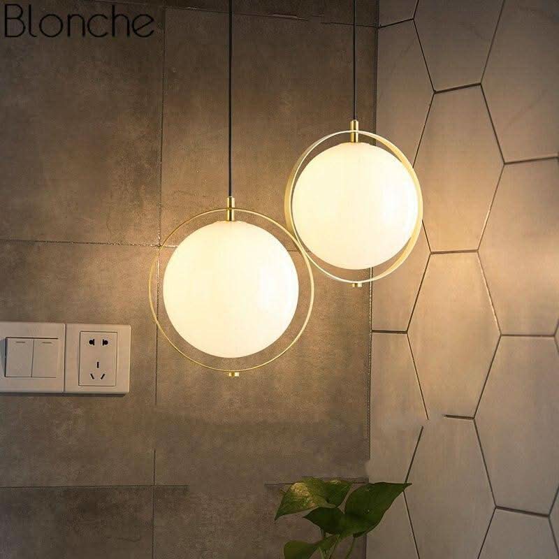 Deux suspensions rondes allumées devant un mur de carrelage hexagonal, ambiance chaleureuse