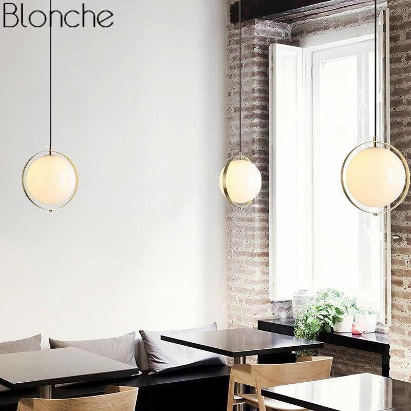 Trois suspensions installées au-dessus de tables dans un café aux murs de briques