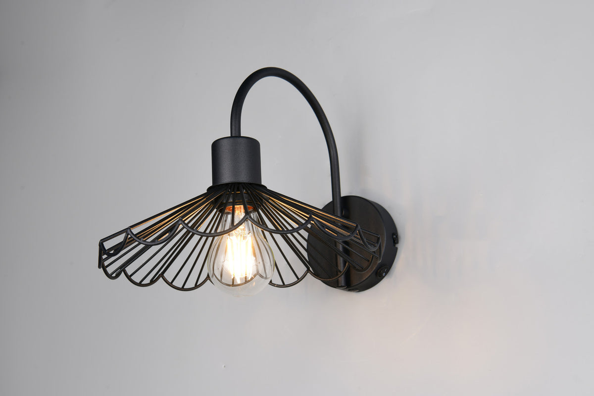 Applique murale noire installée sur un mur gris clair, lumière chaude diffusée par l'ampoule